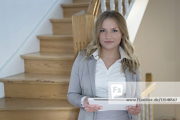 Porträt einer jungen Frau mit digitalem Tablett im Treppenhaus