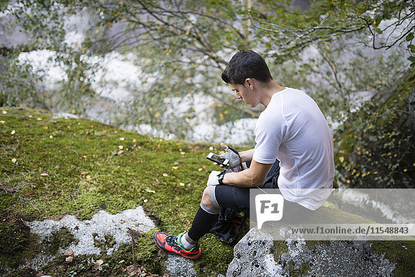 Spanien  A Capela  Cross-Country-Läufer bei einem Blick auf sein Smartphone