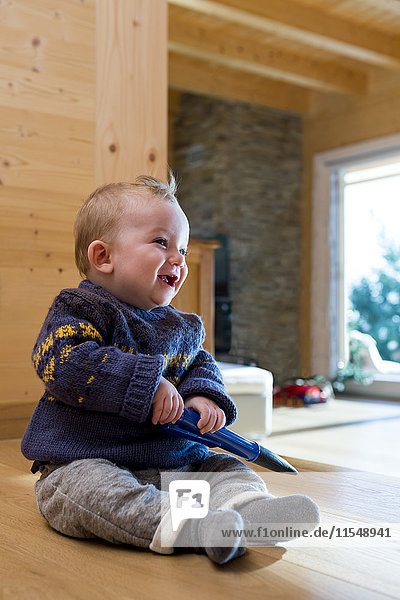Baby Junge sitzt zu Hause auf Holzboden
