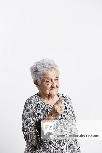 Porträt der erinnernden Seniorin vor weißem Hintergrund