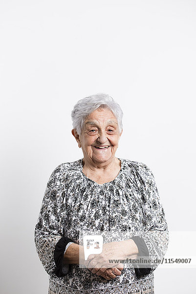 Portrait of happy senior woman in front of white background
