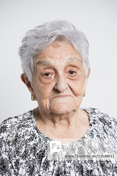 Porträt der traurigen Seniorin vor weißem Hintergrund