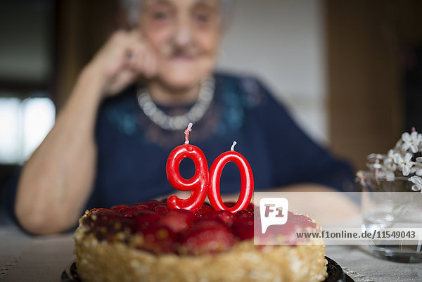 Kerzen auf einem Geburtstagskuchen einer älteren Frau  die ihren neunzigsten Geburtstag feiert.