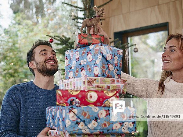 Mann mit einem Stapel Weihnachtsgeschenke  Frau mit Rentier auf dem Kopf