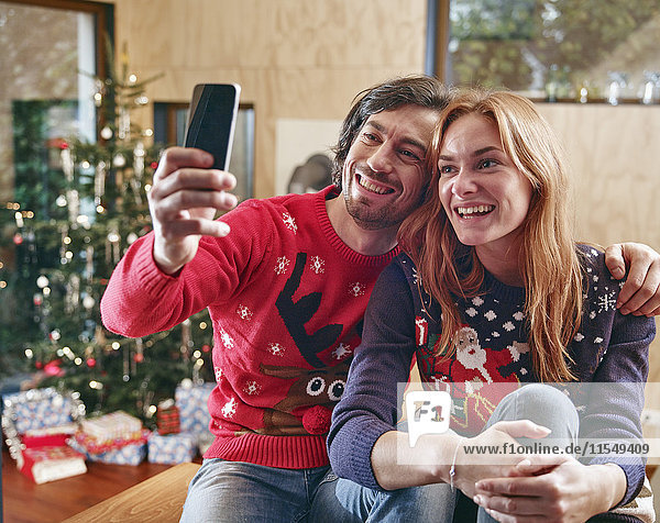 Glückliches Paar nimmt Selfie vor dem Weihnachtsbaum