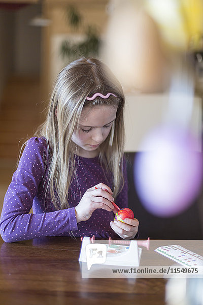 Mädchen malen Osterei zu Hause