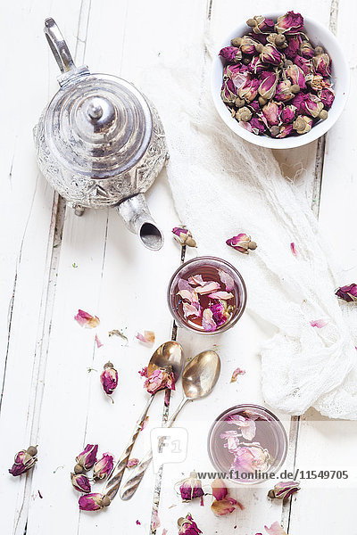 Teekanne und zwei Gläser Rosenblütentee mit getrockneten Rosenblüten