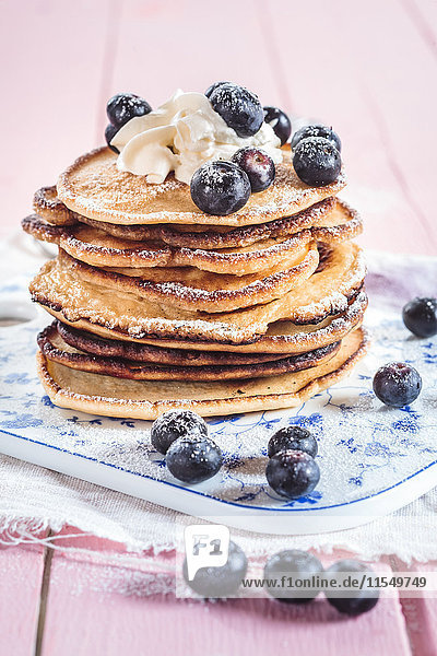 Stack of American pancakes with whipped cream and blueberries