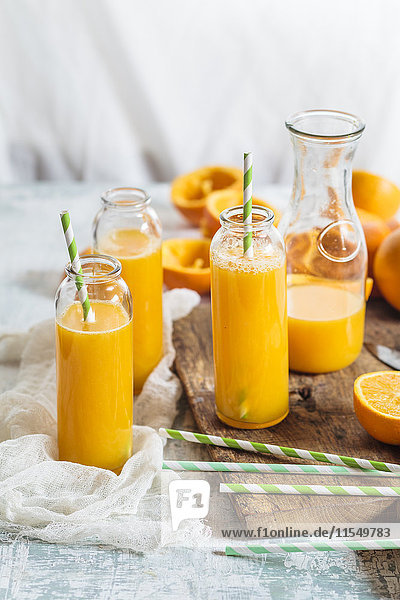 Geschnittene Orangen und Glasflaschen mit frisch gepresstem Orangensaft