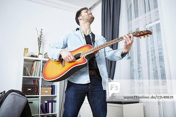 Junger Mann zu Hause beim Gitarrespielen