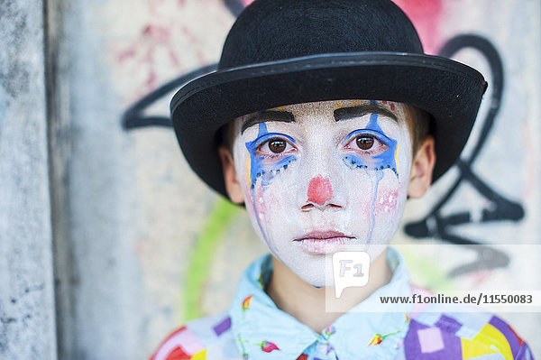 Porträt eines traurigen Jungen  der als Clown gekleidet ist.