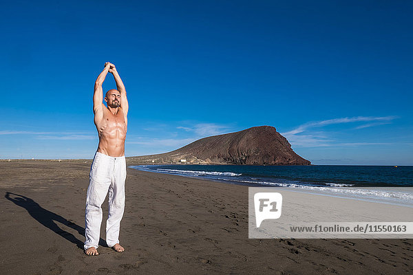 Spanien  Teneriffa  Mann beim Yoga am Strand