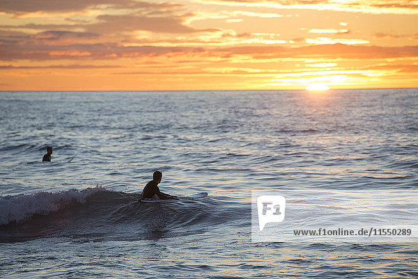 Zwei Surfer bei Sonnenaufgang