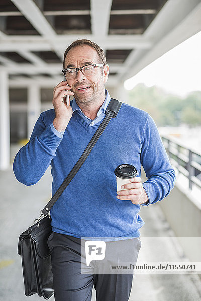 Businessman with cell phone and coffee to go on the move
