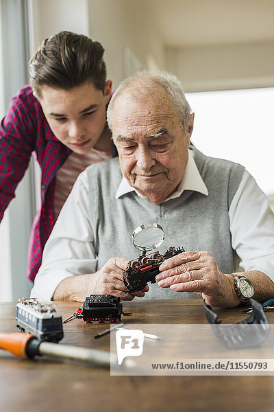 Portrait of senior man and grandson with toy train at home