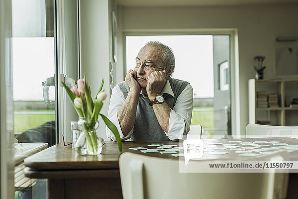 Porträt eines traurigen älteren Mannes mit Blick durchs Fenster