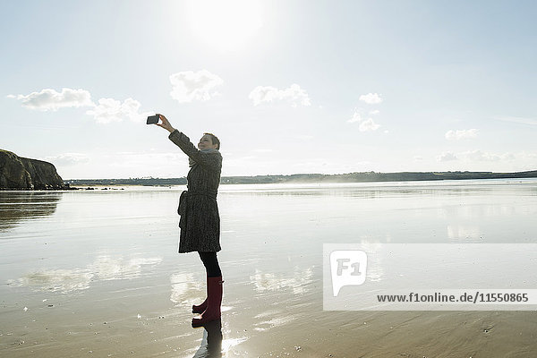 Frankreich  Bretagne  Finistere  Halbinsel Crozon  Frau mit einem Selfie am Strand