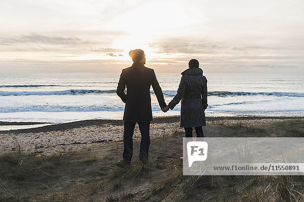 France  Bretagne  Finistere  Crozon peninsula  couple standing at the coast at sunset