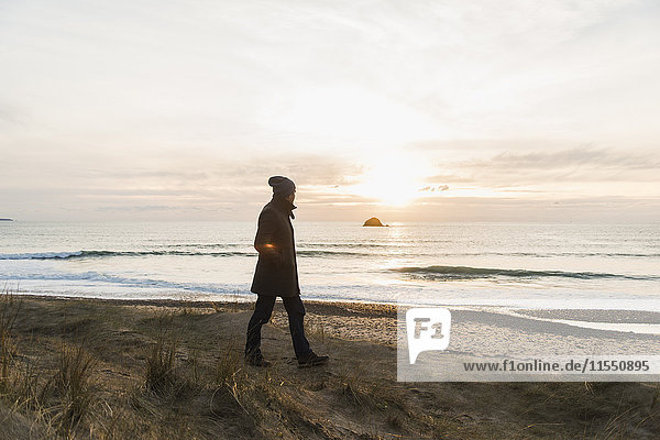 Frankreich  Bretagne  Finistere  Halbinsel Crozon  Mann  der bei Sonnenuntergang an der Küste spazieren geht.