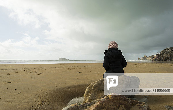 France  Bretagne  Finistere  Crozon peninsula  woman sitting on boulder on the beach