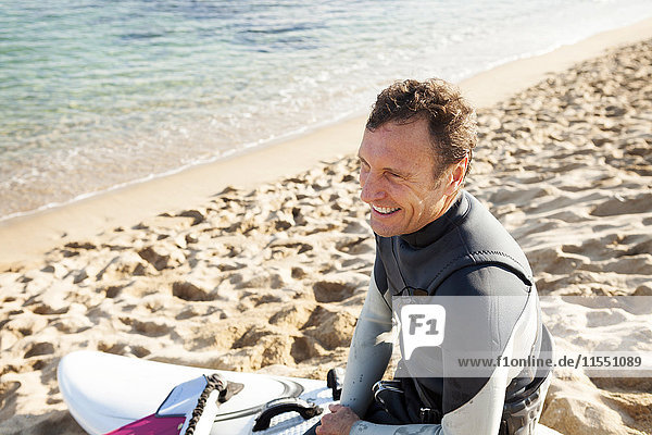 Lächelnder Mann am Strand mit Surfbrett