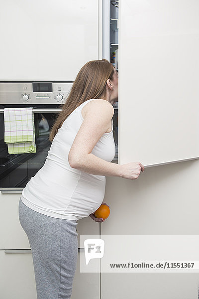 Schwangere Frau schaut in den Kühlschrank