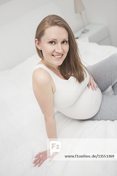 Portrait of smiling pregnant woman on bed