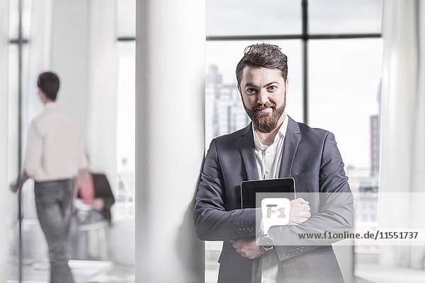 Porträt eines lächelnden Geschäftsmannes mit digitalem Tablett im Büro