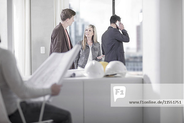 Woman talking to man in office with hard hats on table