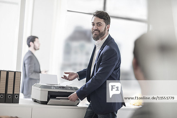 Smiling man in office using printer