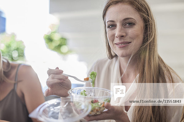 Junge Geschäftsfrau isst Salat zum Mittagessen