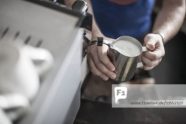 Person preparing milk froth for coffee