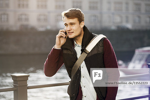 Germany  Berlin  young man on the phone at River Spree