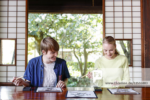 Kaukasisches Paar übt Kalligraphie in einem traditionellen japanischen Haus