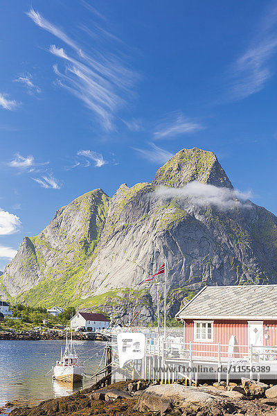 Typisches Fischerhaus namens Rorbu  umrahmt von felsigen Gipfeln und blauem Meer  Reine  Moskenesoya  Lofoten  Norwegen  Skandinavien  Europa