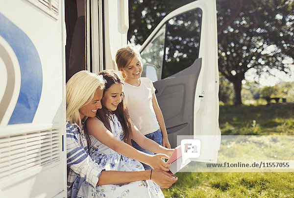 Mutter und Töchter mit digitalem Tablett außerhalb des sonnigen Wohnmobils