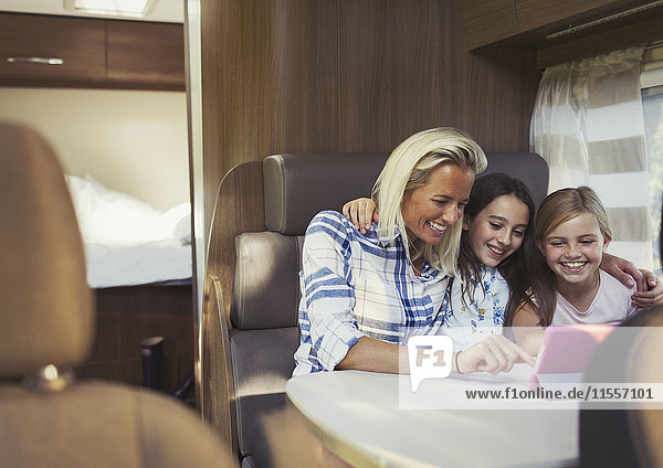 Lächelnde Mutter und Töchter mit digitalem Tablett im Reisemobil