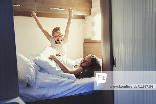 Sisters waking and stretching on bed in motor home