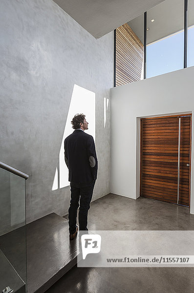 Pensive businessman standing in modern home showcase interior foyer
