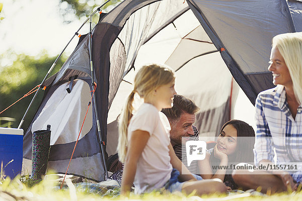 Lächelndes Familiengespräch und Entspannen vor dem sonnigen Zelt