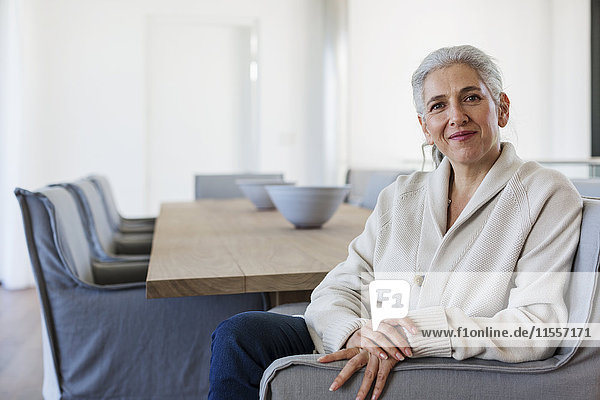 Portrait confident mature woman sitting at dining table