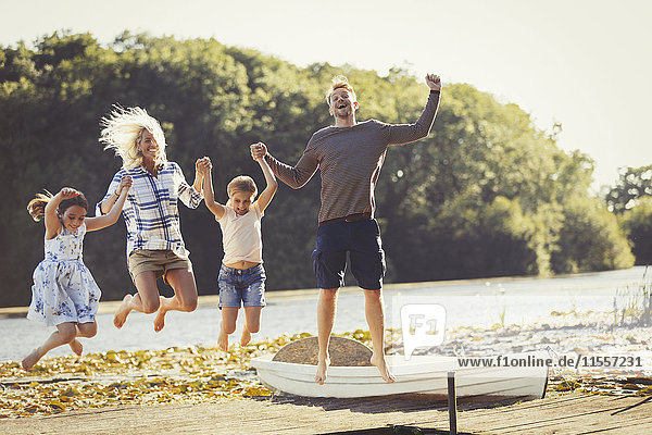 Exuberant family jumping on sunny lake dock