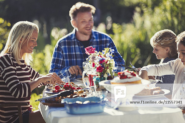 Family eating at sunny garden party patio table