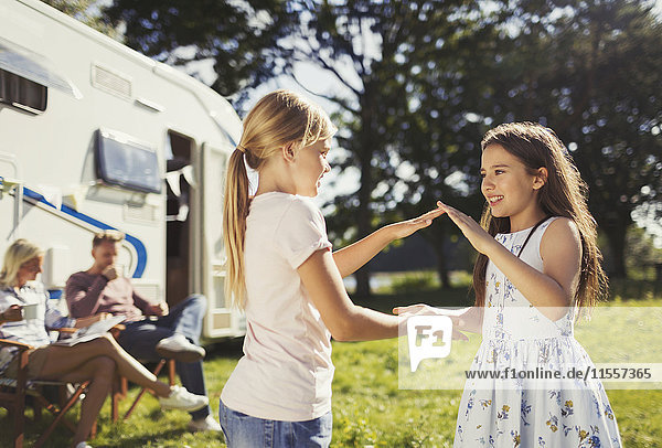 Sisters playing pat-a-cake outside sunny motor home