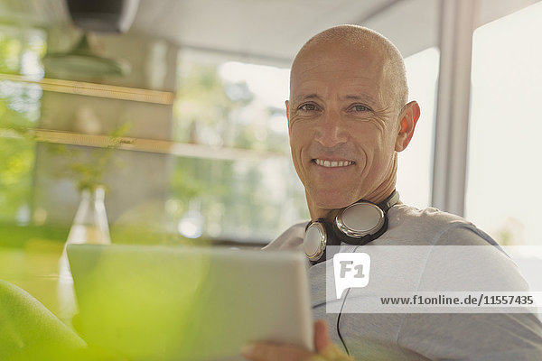 Porträt lächelnder reifer Mann mit Kopfhörern und digitalem Tablet