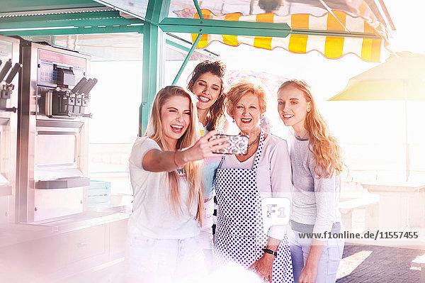 Junge Frauen  die Selfie mit älteren Geschäftsinhabern außerhalb des sonnigen Speisewagens nehmen.
