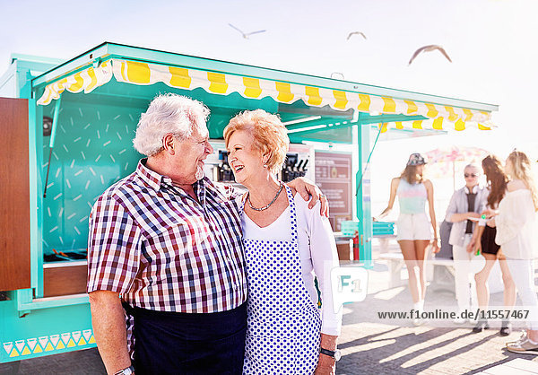 Lächelndes anhängliches älteres Paar Geschäftseigentümer außerhalb des sonnigen Nahrungsmittelwagens