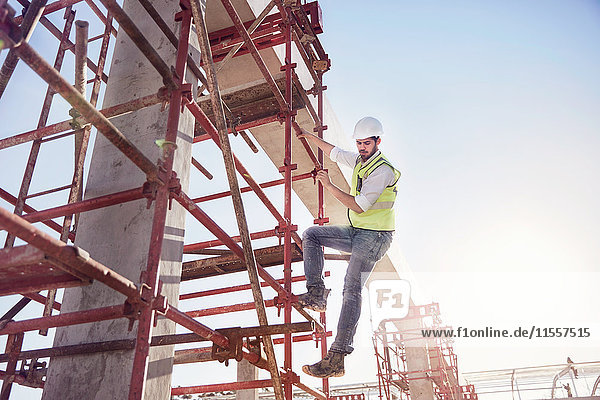 Bauarbeiter klettert auf einer sonnigen Baustelle auf Betonstahl