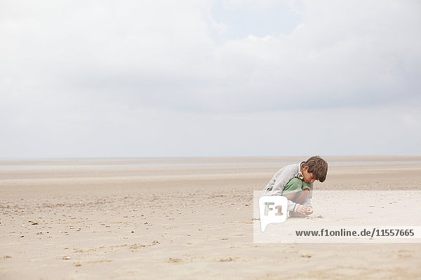 Boy playing in sand on overcast summer beach