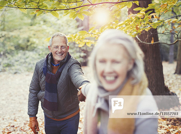 Playful senior couple holding hands in autumn park